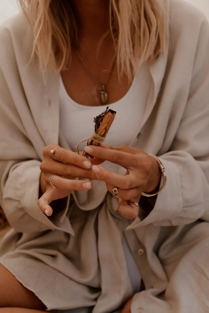 A woman holds a Palo Santo stick, capturing a moment of mindfulness and aroma therapy.